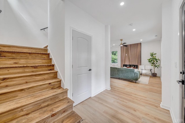 stairway featuring wood finished floors, recessed lighting, and baseboards