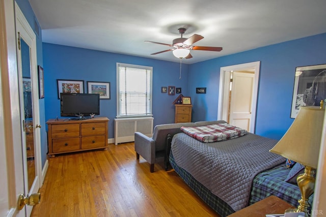 bedroom featuring radiator, wood finished floors, baseboards, and ceiling fan