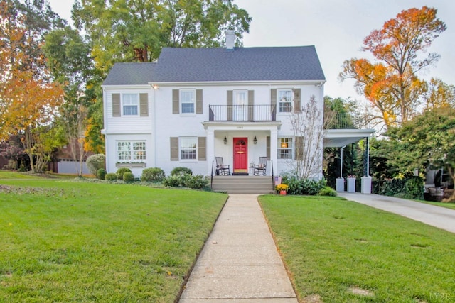 view of front of house featuring a chimney, driveway, a front lawn, an attached carport, and a balcony