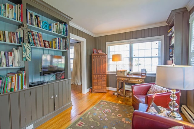 living area featuring ornamental molding, a baseboard radiator, wood finished floors, and baseboards