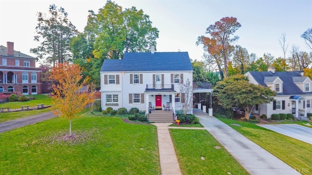 view of front facade with a balcony, driveway, a front lawn, and an attached carport
