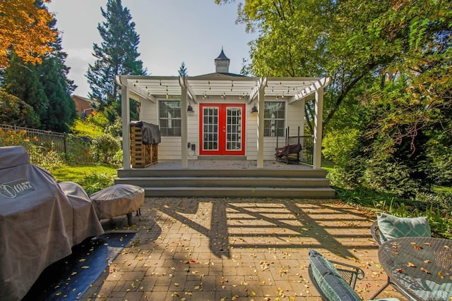 back of property featuring a pergola, a wooden deck, fence, french doors, and a patio area