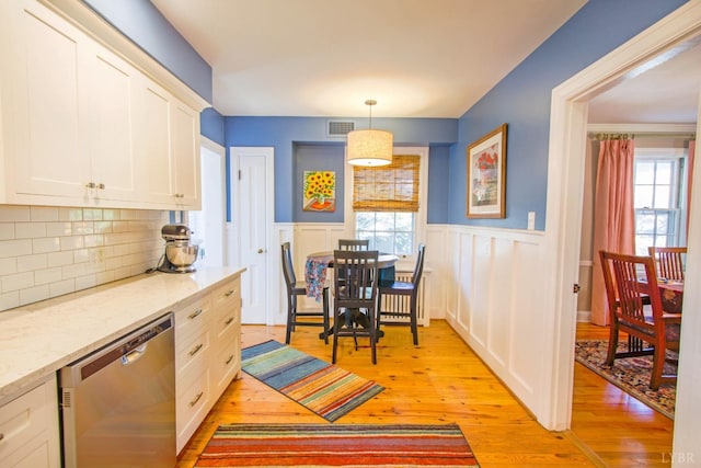 kitchen featuring dishwasher, light wood-style floors, a wainscoted wall, white cabinets, and decorative backsplash
