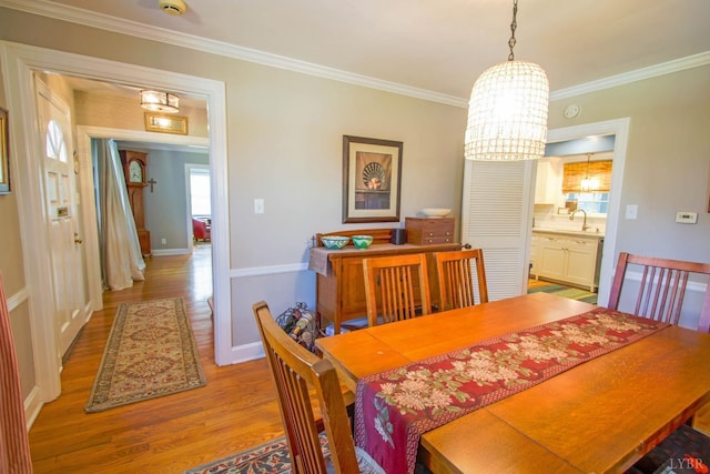 dining space featuring wood finished floors, a chandelier, ornamental molding, and baseboards