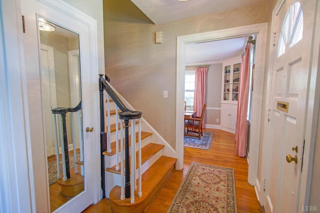 entrance foyer with stairway, wood finished floors, and baseboards