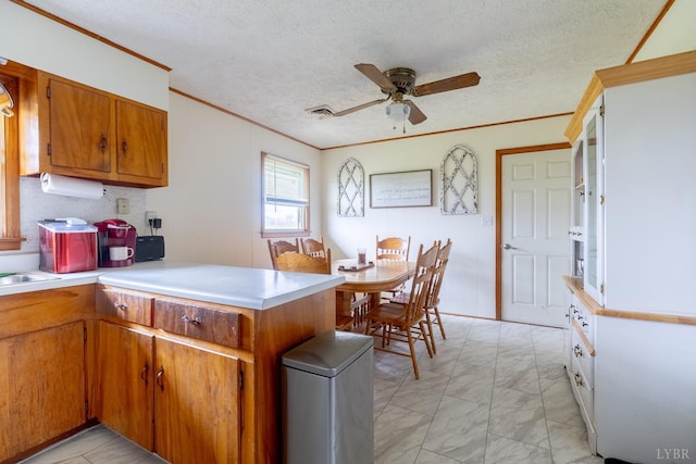 4100 Roark Mill Rd, Hurt, VA 24563 - kitchen with crown molding, a peninsula, light marble finish floors, ceiling fan, and brown cabinets