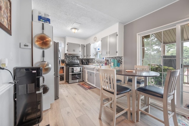 500 Leftwich St, Gretna, VA 24557 - kitchen featuring stainless steel appliances, light wood-style floors, tasteful backsplash, gray cabinets, and under cabinet range hood