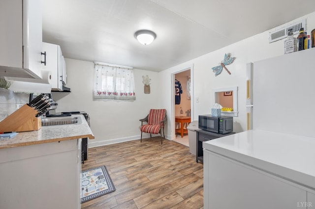 500 Leftwich St, Gretna, VA 24557 - kitchen featuring freestanding refrigerator, light countertops, light wood-type flooring, white cabinets, and baseboards
