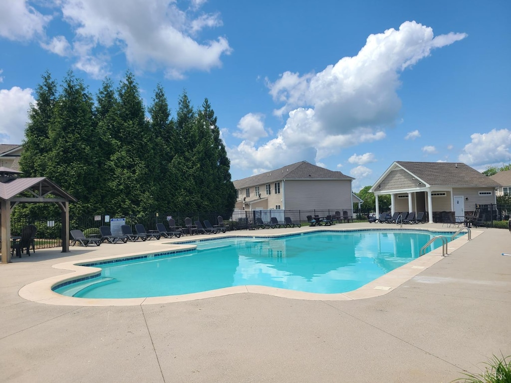 community pool featuring fence, a patio, and a gazebo