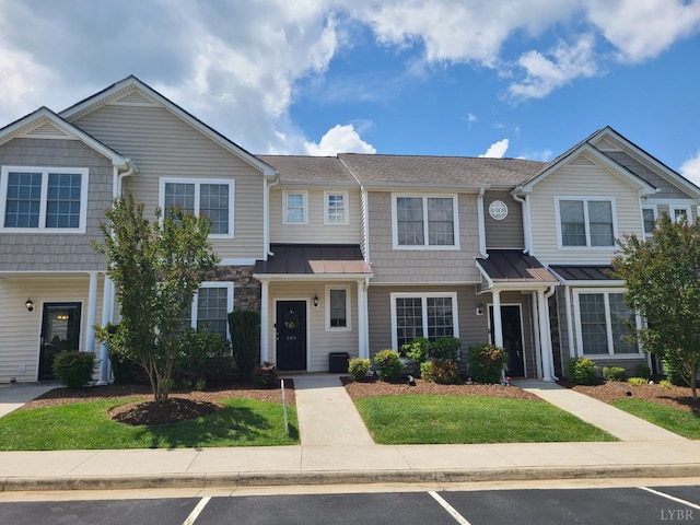 view of property with a front lawn, a standing seam roof, and uncovered parking