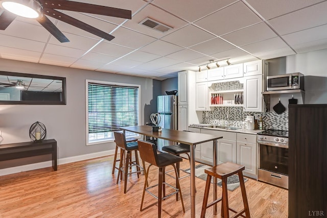 206 Bella Ct, Lynchburg, VA 24502 - kitchen featuring stainless steel appliances, ceiling fan, light wood finished floors, tasteful backsplash, and a drop ceiling