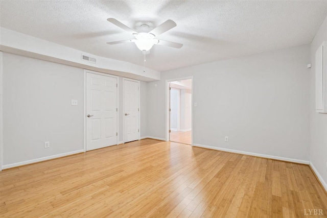 112 Cedarwood Ct, Forest, VA 24551 - unfurnished bedroom with light wood-style floors, baseboards, a textured ceiling, and two closets
