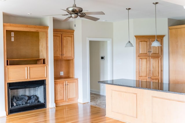 126 Golf Course Trl, Amherst, VA 24521 - kitchen featuring dark stone countertops, ceiling fan, decorative light fixtures, a fireplace, and light wood finished floors