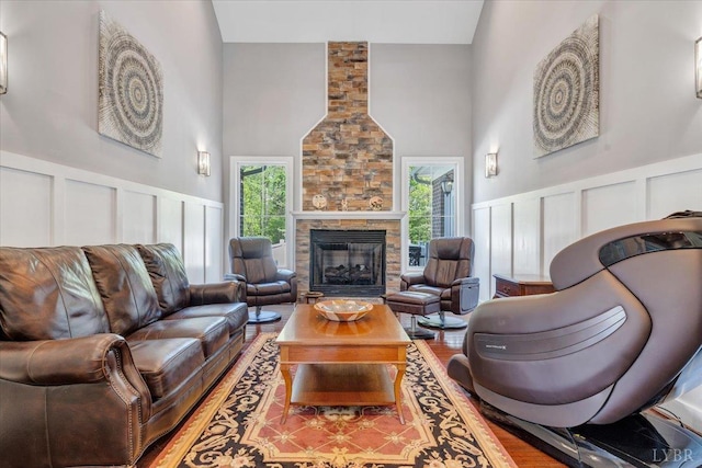 1037 Deer Hollow Rd, Forest, VA 24551 - living room with a decorative wall, high vaulted ceiling, a stone fireplace, wainscoting, and wood finished floors