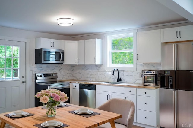 1001 3rd St, Lynchburg, VA 24504 - kitchen with appliances with stainless steel finishes, a sink, white cabinetry, butcher block countertops, and tasteful backsplash