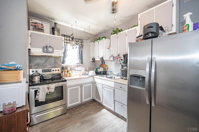 1706 Union St, Lynchburg, VA 24504 - kitchen with appliances with stainless steel finishes, under cabinet range hood, light countertops, white cabinets, and light wood-type flooring