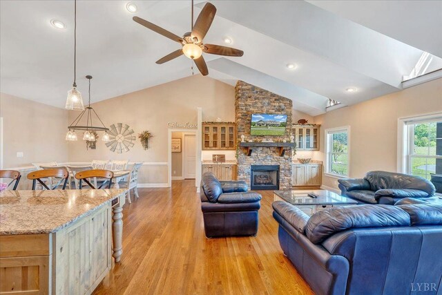 20438 Wyatts Way, Evington, VA 24550 - living area featuring light wood-style floors, ceiling fan, a stone fireplace, baseboards, and high vaulted ceiling