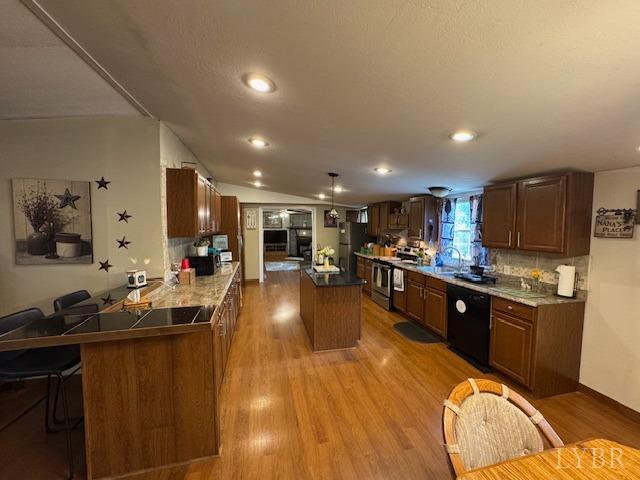 3164 Trent Hatchery Rd, Appomattox, VA 24522 - kitchen with appliances with stainless steel finishes, a kitchen island, wood finished floors, a sink, and a peninsula