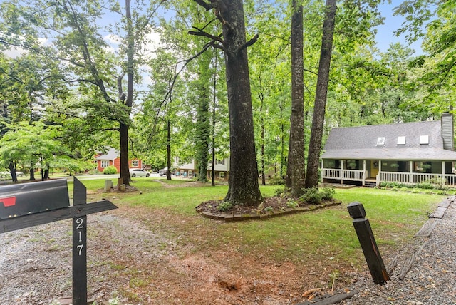 view of green lawn featuring covered porch