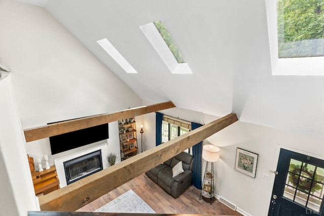 living room with wood finished floors, a fireplace, a skylight, and high vaulted ceiling