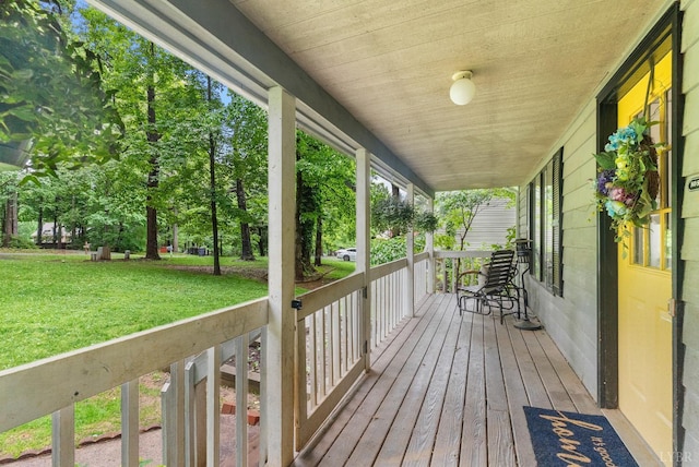 wooden terrace featuring covered porch and a lawn