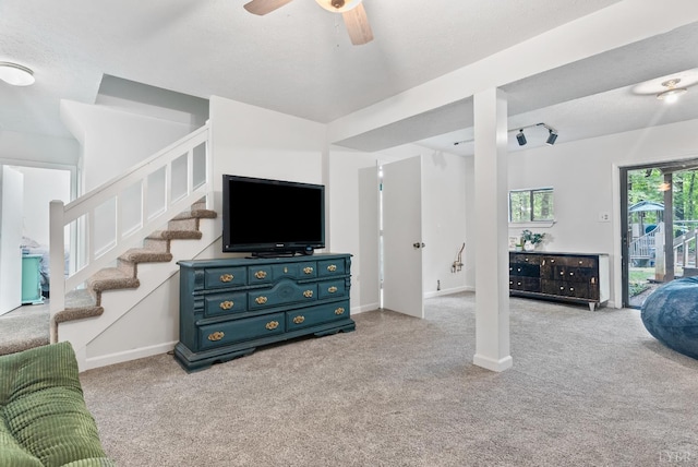 living area with light colored carpet, ceiling fan, stairs, and baseboards
