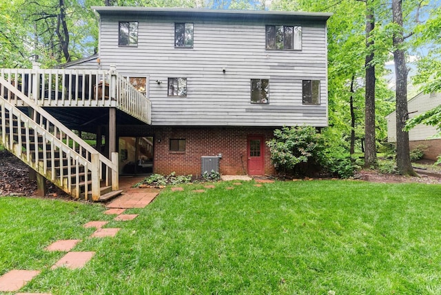 back of property with a yard, a deck, cooling unit, and brick siding