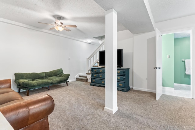 carpeted living area featuring ceiling fan, a textured ceiling, stairway, and baseboards