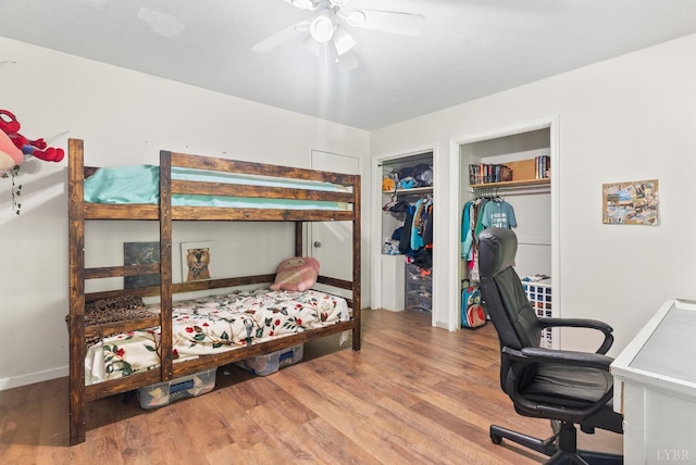 bedroom featuring wood finished floors, an office area, and a ceiling fan