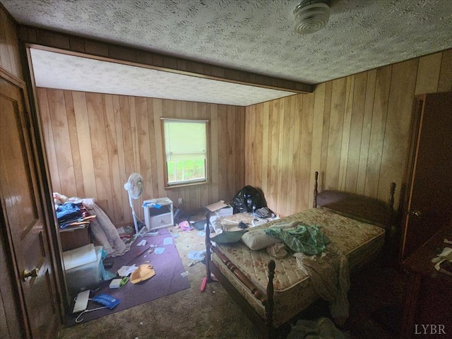 bedroom with a textured ceiling, carpet, and wooden walls
