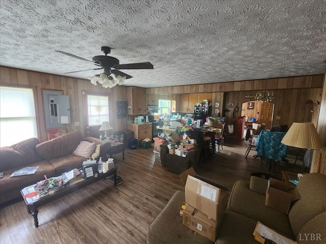 living area featuring wooden walls, ceiling fan, a textured ceiling, and wood finished floors
