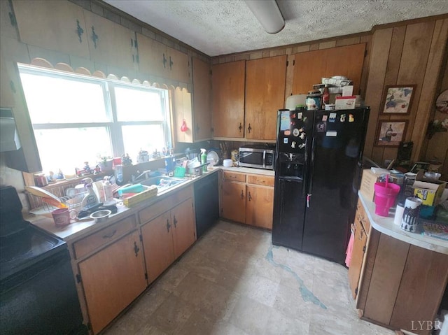 kitchen with black refrigerator with ice dispenser, stainless steel microwave, a textured ceiling, light countertops, and brown cabinets