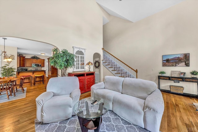1309 W Pine Ridge Rd, Huddleston, VA 24014 - living area with arched walkways, light wood finished floors, stairs, a high ceiling, and a chandelier