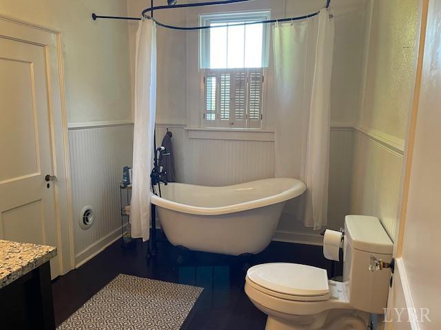 202 Leftwich St, Gretna, VA 24557 - bathroom with a wainscoted wall, a freestanding bath, toilet, a decorative wall, and vanity