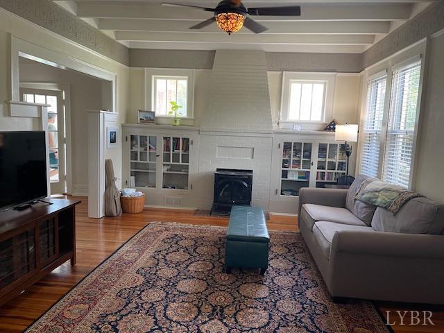 202 Leftwich St, Gretna, VA 24557 - living room featuring wood finished floors, a ceiling fan, beam ceiling, and a wood stove