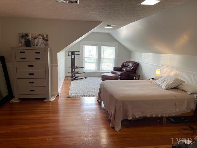 202 Leftwich St, Gretna, VA 24557 - bedroom with wood finished floors, vaulted ceiling, a textured ceiling, and wainscoting