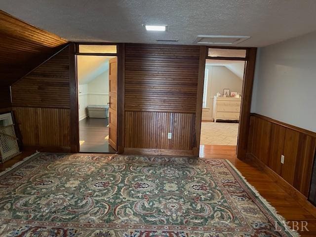 202 Leftwich St, Gretna, VA 24557 - unfurnished bedroom with attic access, wooden walls, wood finished floors, a textured ceiling, and a wainscoted wall