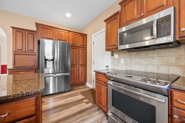 3374 Goode Station Rd, Goode, VA 24556 - kitchen featuring stainless steel appliances, arched walkways, dark stone countertops, brown cabinetry, and recessed lighting