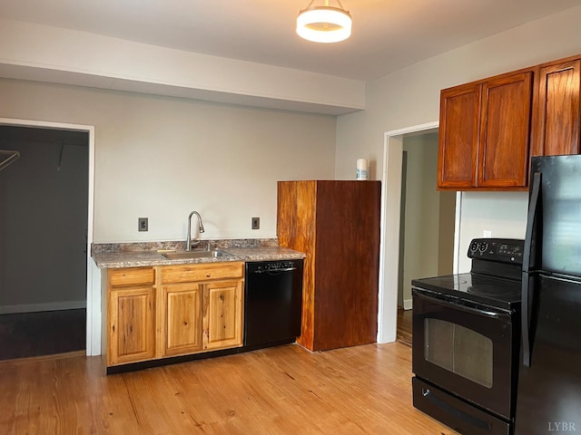 kitchen with black appliances, a sink, light wood-type flooring, and brown cabinets