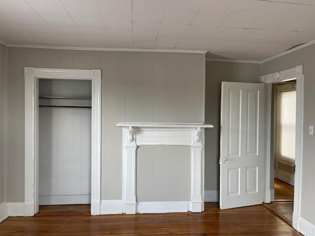 unfurnished bedroom with wood finished floors, ornamental molding, and a closet