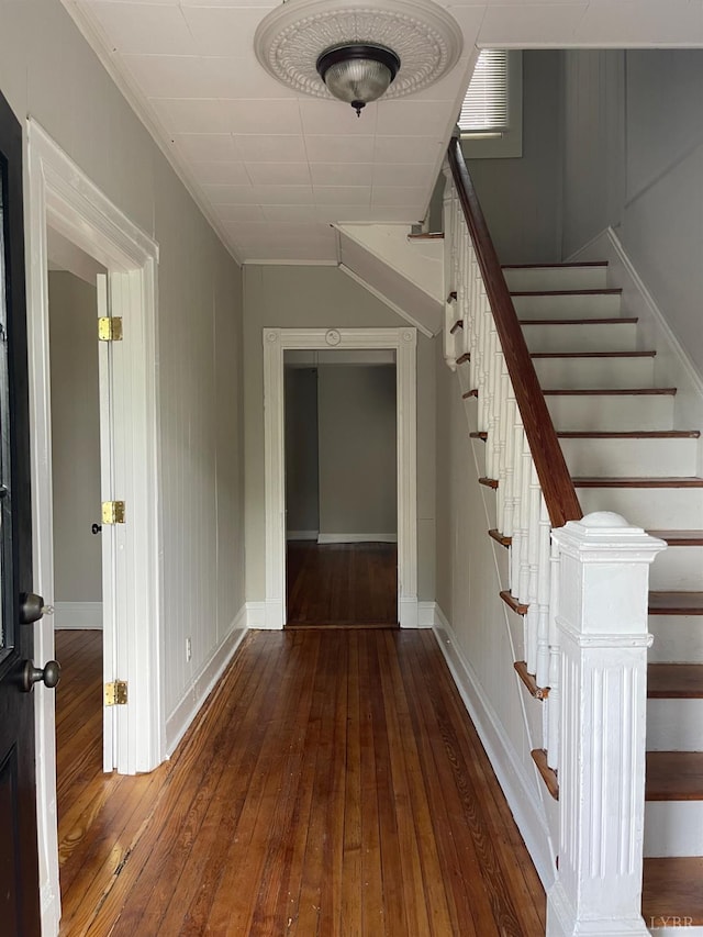 stairs featuring hardwood / wood-style floors, baseboards, and crown molding