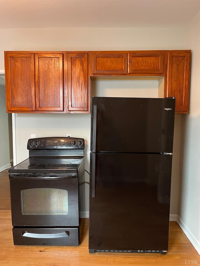 kitchen with black appliances, light wood finished floors, brown cabinets, and baseboards