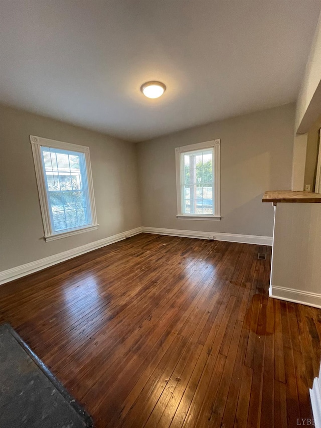 spare room with dark wood finished floors and baseboards