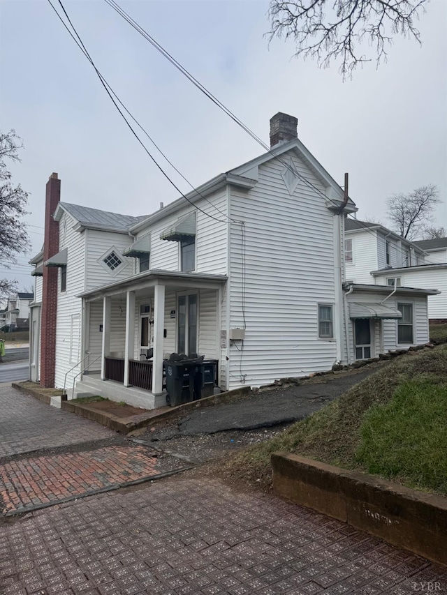 view of property exterior with covered porch and a chimney