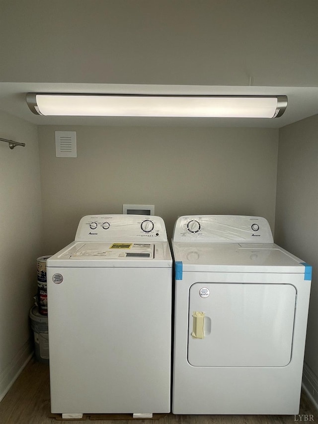laundry area featuring washer and clothes dryer, baseboards, and wood finished floors