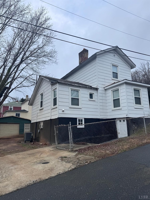 view of side of home with a chimney and central AC unit