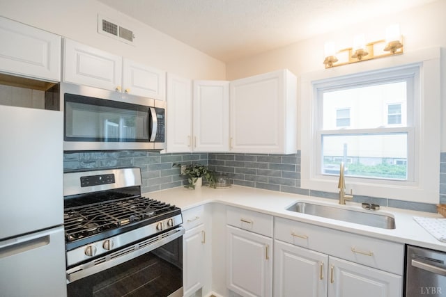 3501 Fort Ave Unit 27, Lynchburg, VA 24501 - kitchen with stainless steel appliances, a sink, white cabinets, and decorative backsplash