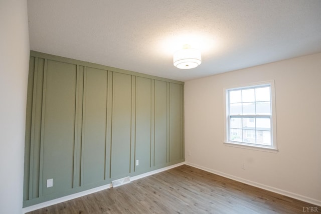 3501 Fort Ave Unit 27, Lynchburg, VA 24501 - empty room featuring light wood-style floors, baseboards, a textured ceiling, and a decorative wall