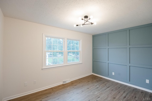 3501 Fort Ave Unit 27, Lynchburg, VA 24501 - unfurnished bedroom with a chandelier, wood finished floors, a textured ceiling, a decorative wall, and baseboards