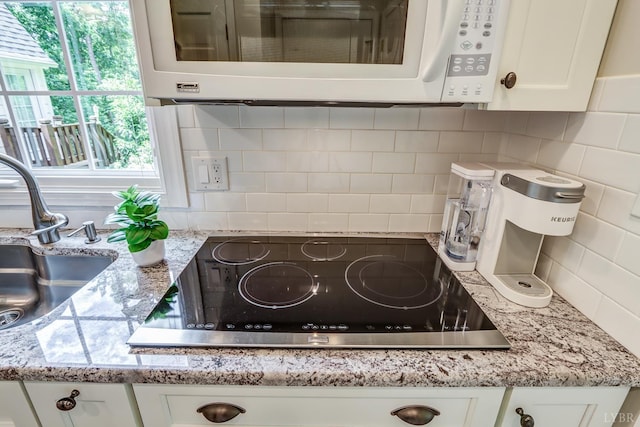 1146 Audubon Dr, Lynchburg, VA 24503 - kitchen view of white microwave, black electric stovetop, backsplash, white cabinets, and a sink